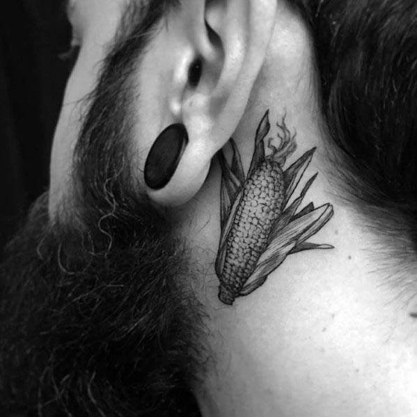 Black and gray tattoo of a detailed corn cob with husks, placed behind the ear, creating a bold yet subtle design.