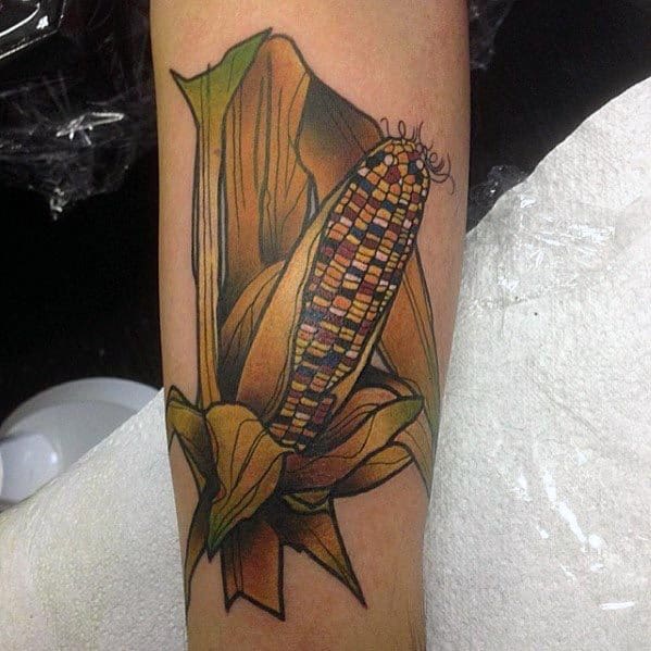 Bold tattoo of an Indian corn cob with rich multicolored kernels and dried husks, featuring intricate shading and vibrant details.