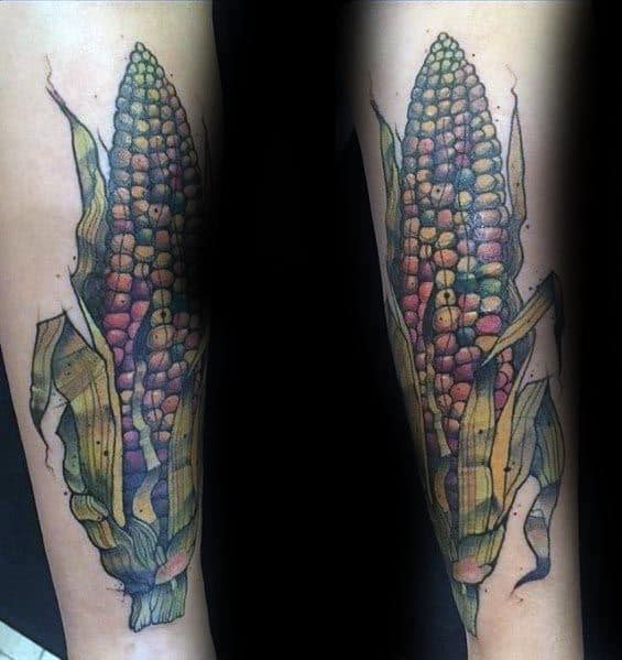 Detailed tattoo of an Indian corn cob with multicolored kernels and weathered husks, designed with bold shading and a realistic touch.