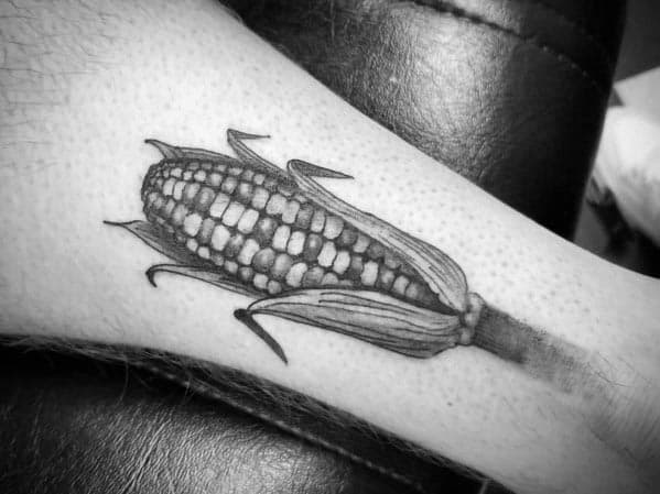 Black and gray tattoo of a detailed corn cob with husks, featuring fine shading and realistic texture for a classic design.