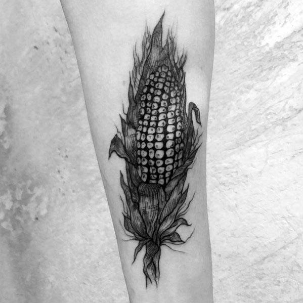 Black and gray tattoo of a corn cob with husks, featuring bold shading and a fiery effect for a striking and artistic design.