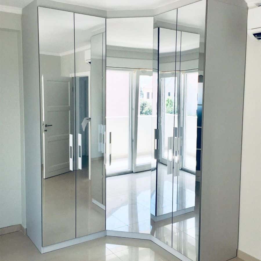Large mirrored corner bedroom closet with modern handles.