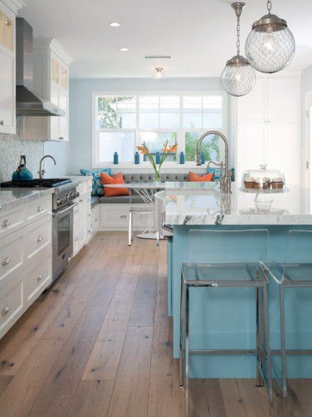 Bright kitchen with light blue accents, island, clear chairs, and a cozy window nook with colorful cushions