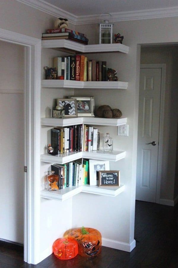 White corner built-in shelves with books, decor, and framed photos in a cozy hallway nook.