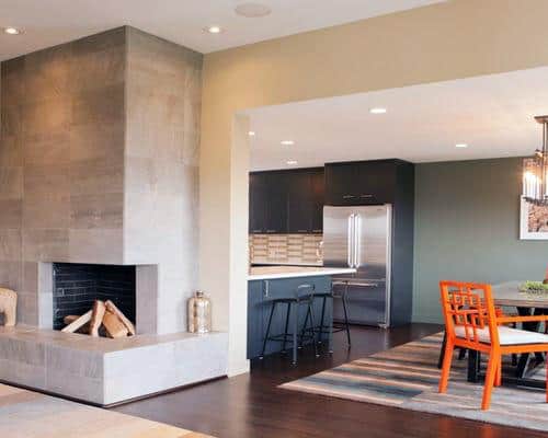 Modern open-plan space with concrete corner fireplace, dark wood flooring, and vibrant dining area.