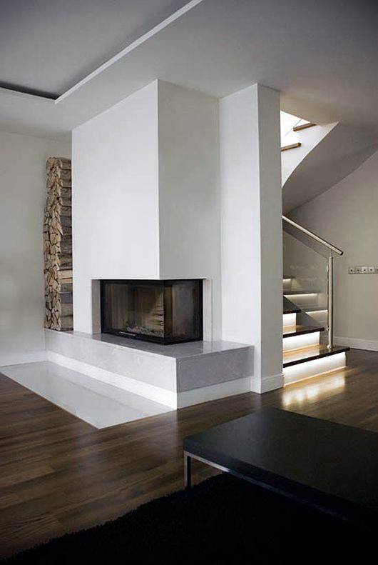 Modern corner fireplace with glass panels, built-in firewood storage, and dark wood flooring.