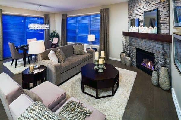 Modern living room with stone corner fireplace, dark wood mantel, beige sofa, and cozy decor.