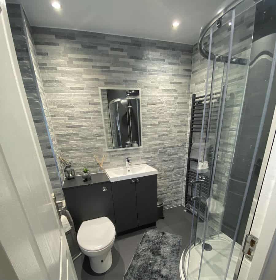 small corner shower in gray tile bathroom