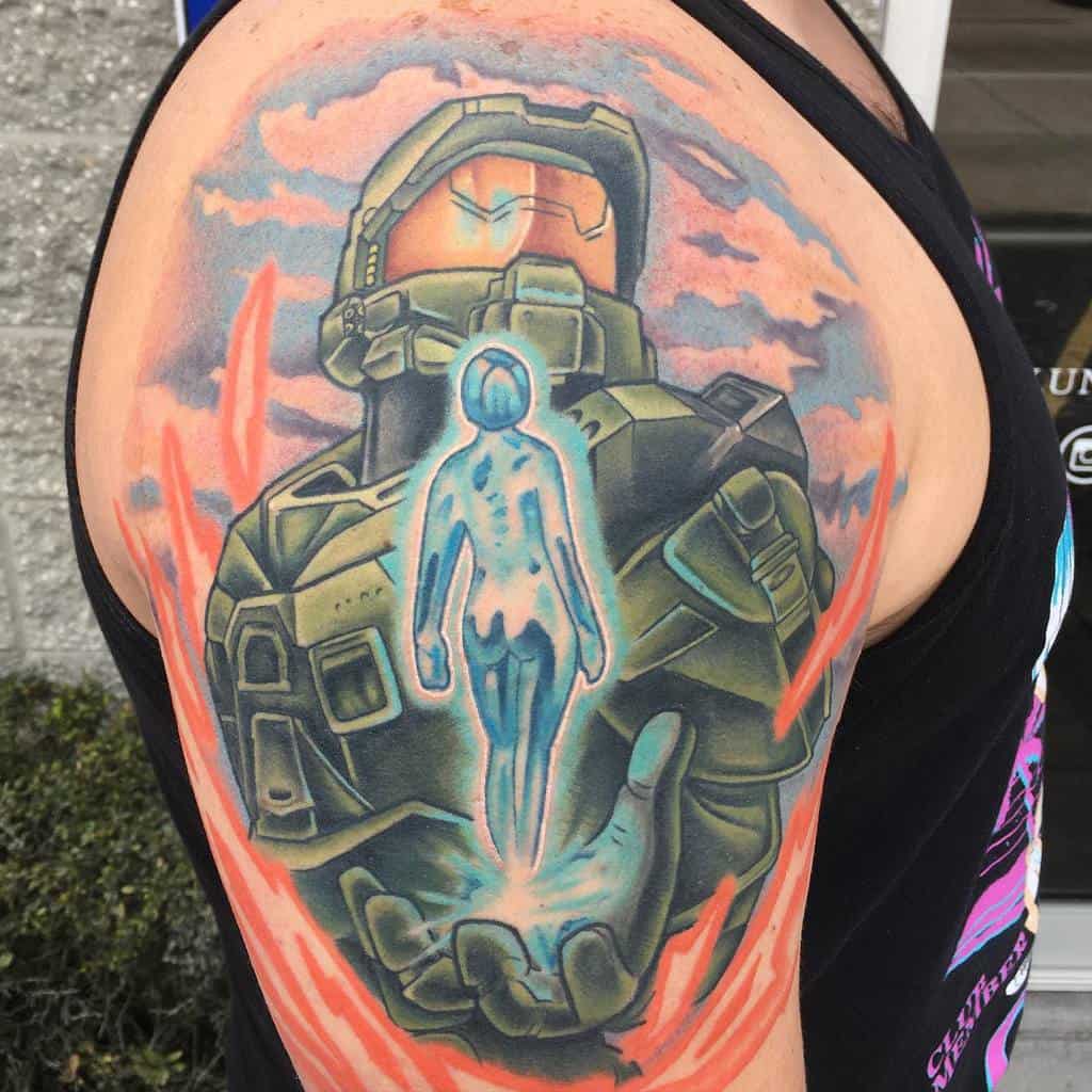 Colorful Halo tattoo of Master Chief holding Cortana’s glowing hologram, surrounded by fiery energy, inked on the upper arm.