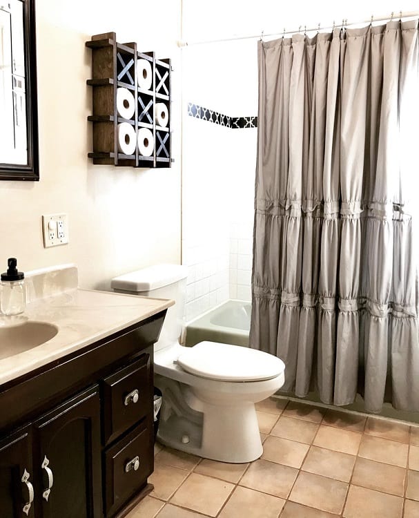 Farmhouse bathroom with shower curtain, toilet, dark wood vanity, and wall-mounted toilet paper holder