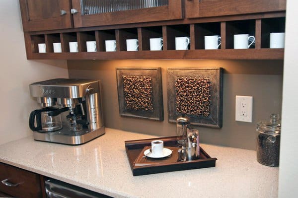 Coffee bar with wooden cabinets, built-in mug storage, espresso machine, and decorative wall art.