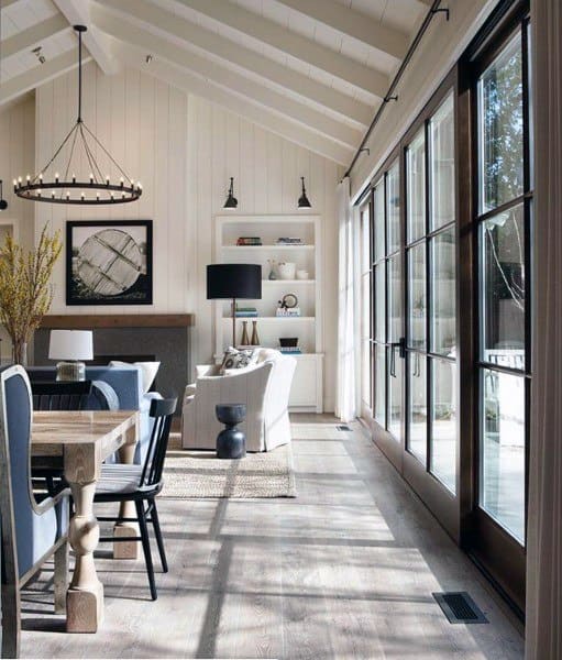 Bright modern living and dining space with vaulted ceiling, concrete floors, large windows, and stylish decor