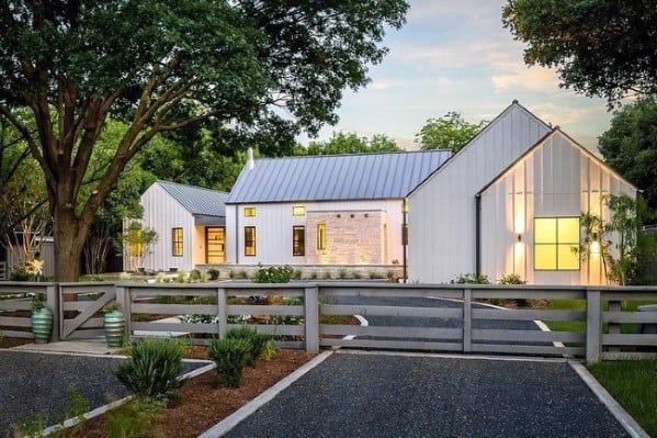 Gravel driveway with white concrete borders leading to a modern farmhouse-style home.