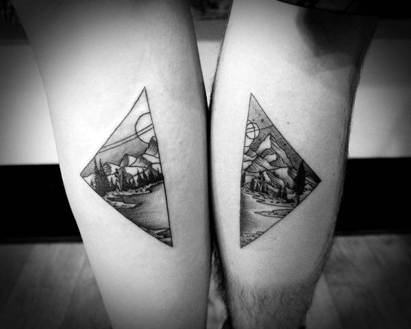 Matching tattoos of a mountain and forest landscape split into two diamond shapes, forming a complete scenic view when together.