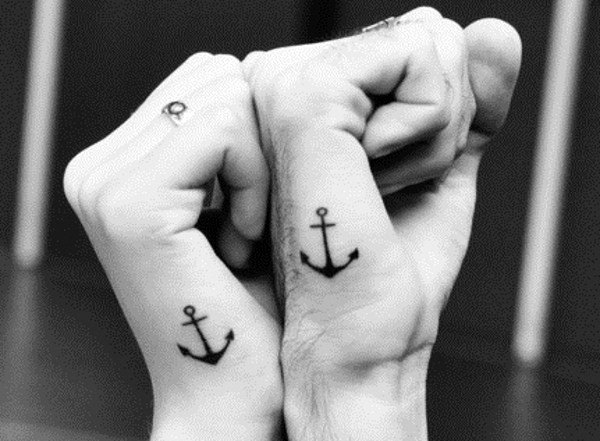 Matching small anchor tattoos on wrists, symbolizing stability, grounding, and a love that holds strong through all tides.