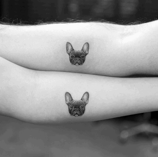 Matching forearm tattoos of a French Bulldog's face, symbolizing shared love for a pet and a playful bond between the couple.