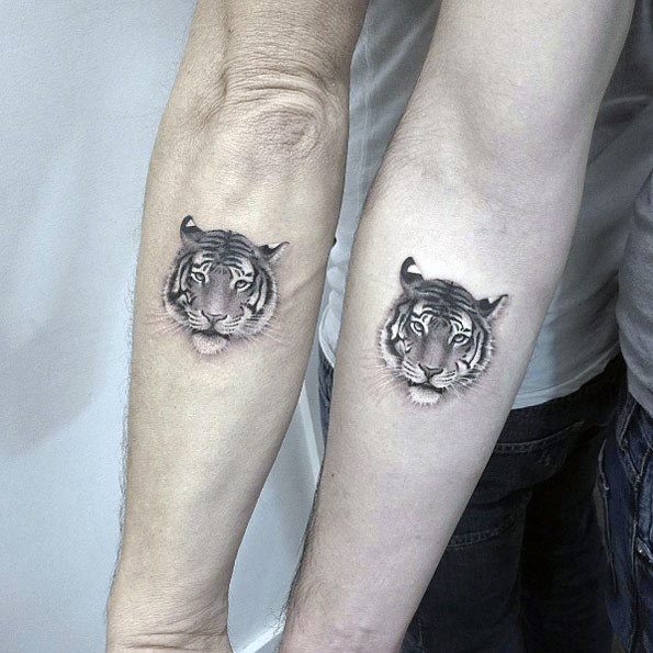 Matching forearm tattoos of a realistic tiger face, symbolizing strength, courage, and a powerful connection between the couple.