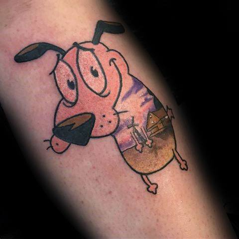 Courage the Cowardly Dog tattoo with a serene look, featuring a sunset and house scene subtly blended into his body.