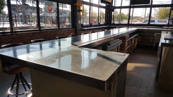 Industrial-style bar with sleek concrete countertop and large windows for natural light.