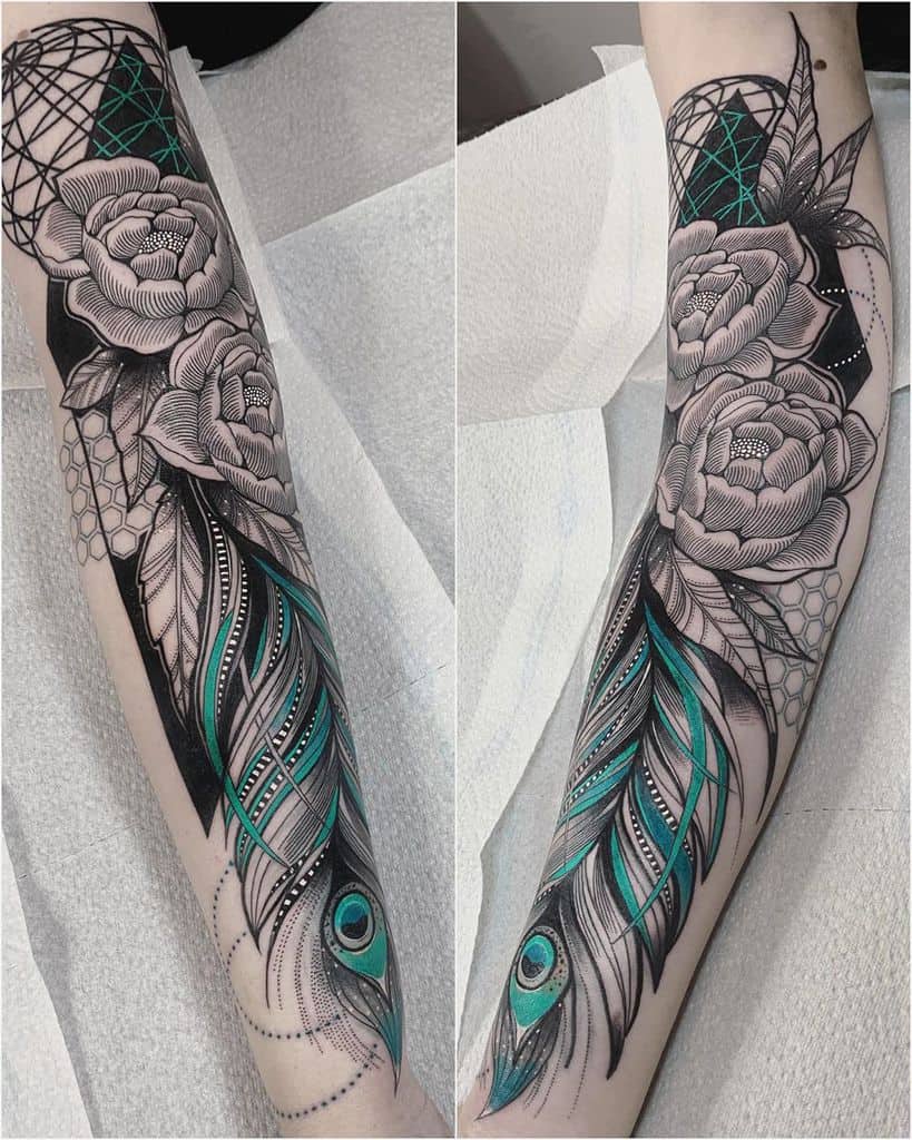 Intricate black and grey forearm tattoo featuring detailed roses, geometric patterns, and stylized peacock feathers with bold teal accents.