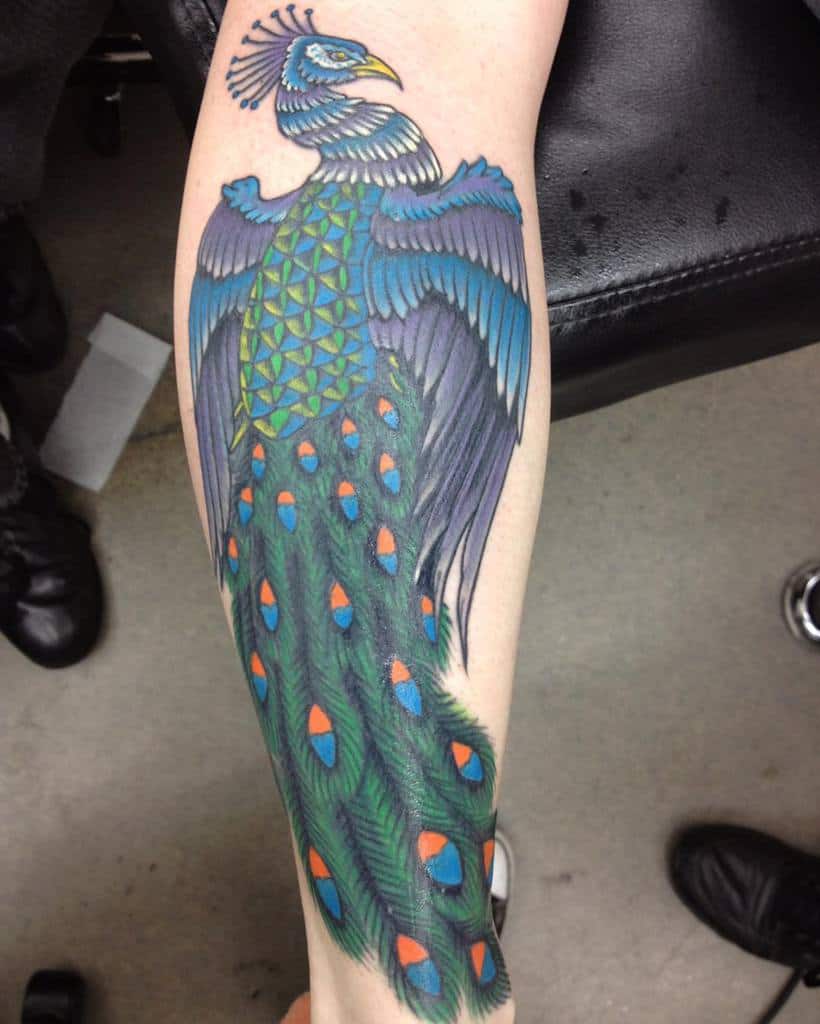 Peacock tattoo with intricate blue, green, and orange feathers, detailed tail, and geometric pattern on the chest.