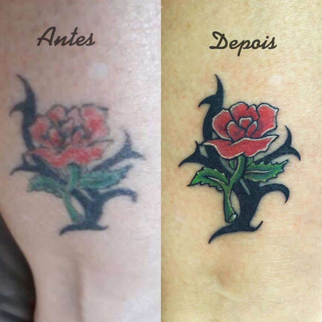 A cover-up tattoo showing a rose with vibrant red and green colors, surrounded by bold black tribal ink, transforming an older design into a fresh, striking piece