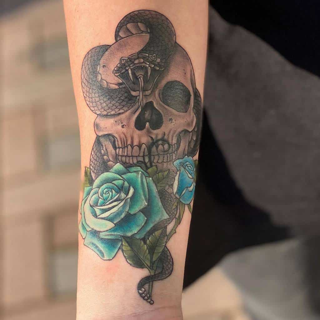 Forearm tattoo featuring a skull entwined with a coiled snake and vibrant blue roses, blending realism and symbolic elements.