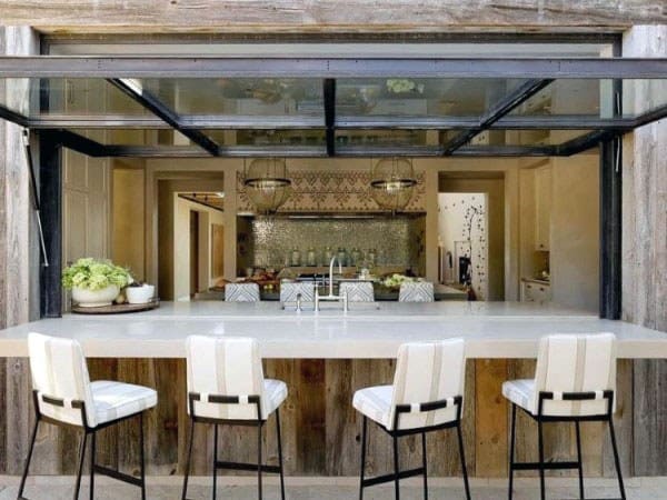 Sleek wood pallet bar with a white countertop, modern barstools, and a retractable glass door.
