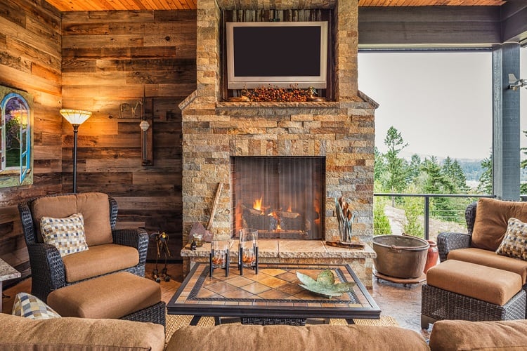 cabin style living room with wood shiplap walls and stone fireplace