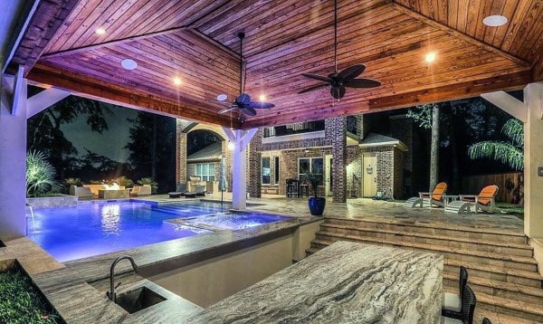 Backyard with a covered pool, stone bar countertop, wooden ceiling, and cozy lounge areas.