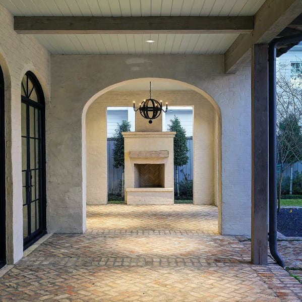 Brick patio with flooring and a large fireplace, all under a round chandelier
