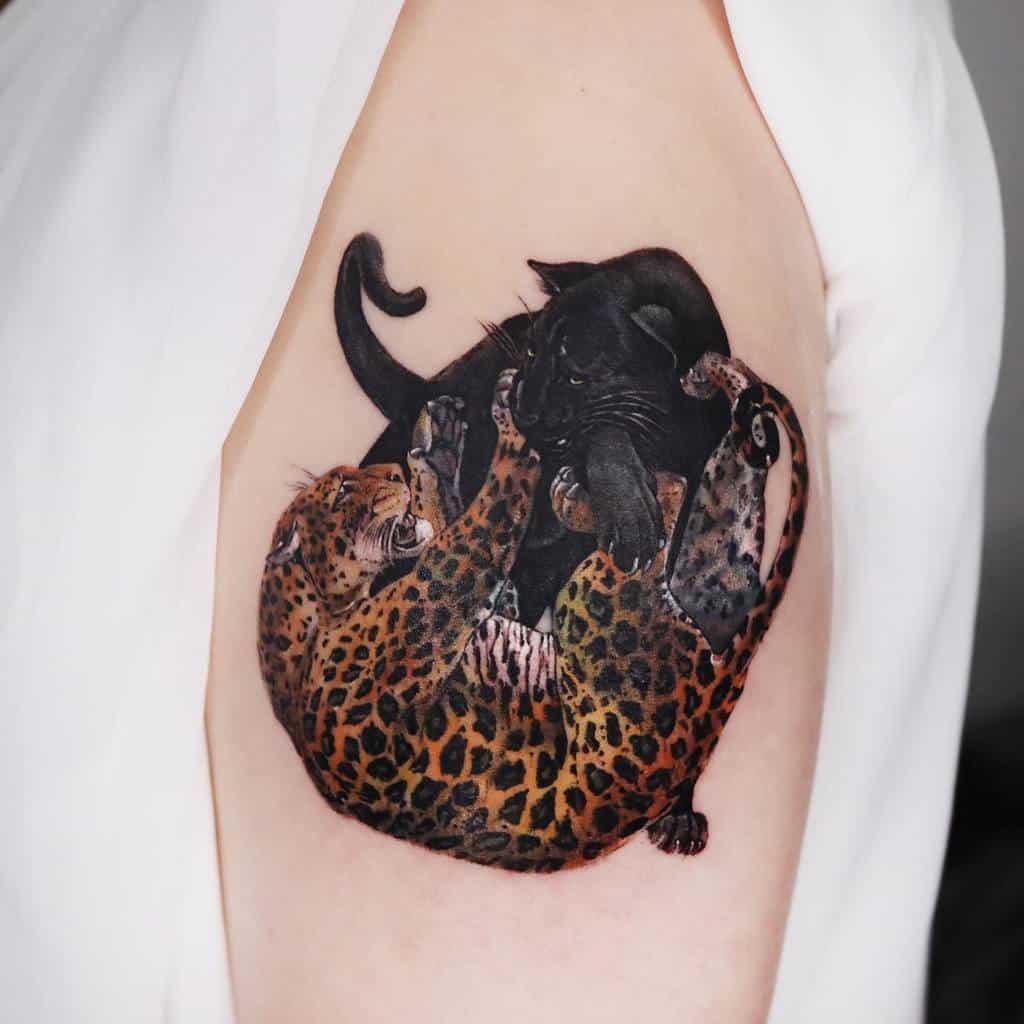 A vibrant tattoo of a jaguar and a black panther playfully wrestling, featuring bold colors and intricate shading on the upper arm.