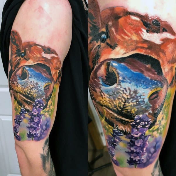Colorful cow tattoo with a surreal landscape reflected in its eye, surrounded by purple flowers and vivid painterly brushstrokes.