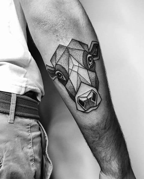 Geometric cow head tattoo on forearm with bold lines and dotwork shading, creating a modern, angular 3D effect.