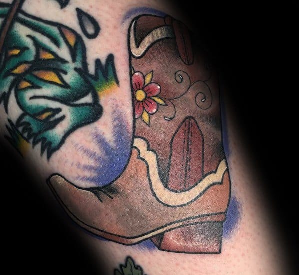 Tattoo of a Western-style cowboy boot with floral details, blending rustic charm with a touch of elegance in a bold, colorful design.
