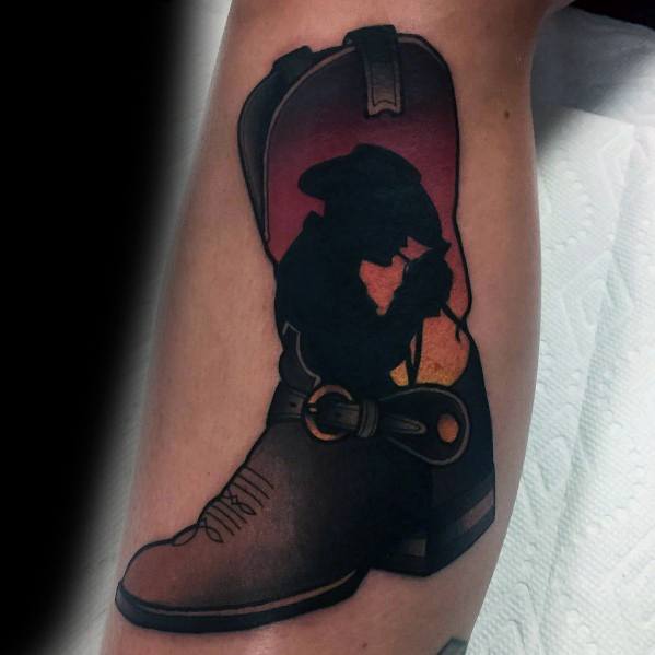 Tattoo of a cowboy boot featuring a sunset silhouette of a cowboy tipping his hat, blending Western heritage with a bold, artistic touch.