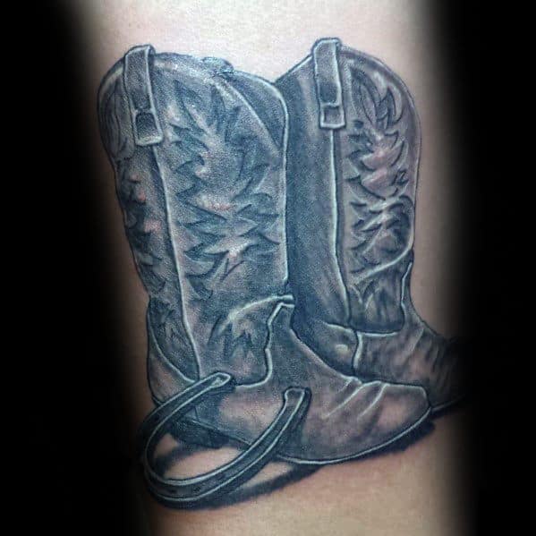 Tattoo of a pair of worn cowboy boots with spurs, symbolizing resilience, hard work, and a deep connection to Western heritage.