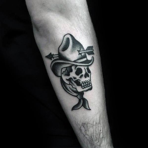 Black and gray tattoo of a cowboy skull wearing a hat and bandana, pierced by an arrow, done in a bold Western style with smooth shading.