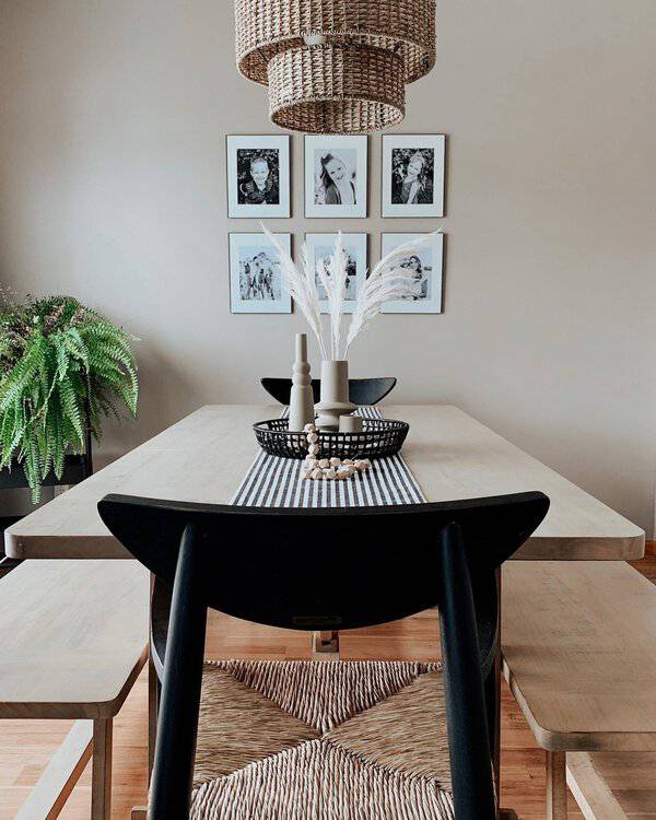 Boho dining room with natural materials, woven lighting, black chairs, and a minimalist table setting.