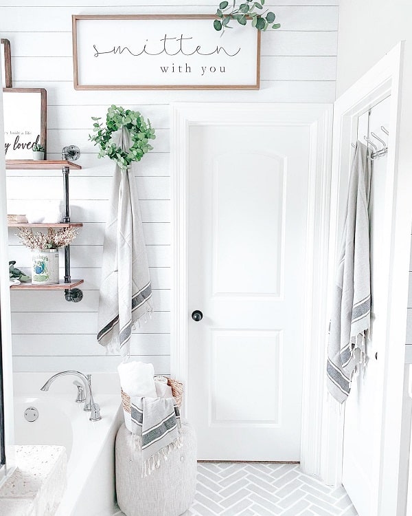 Farmhouse-style bathroom with shiplap walls, a "smitten with you" sign, and cozy decor