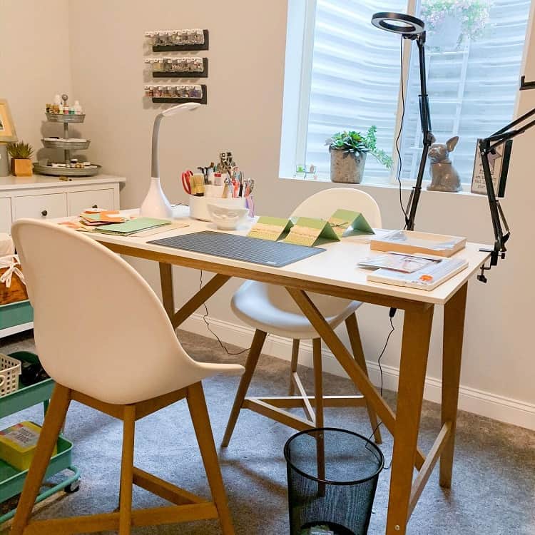 Cozy craft room with a white desk, chair, art supplies, and a window letting in natural light