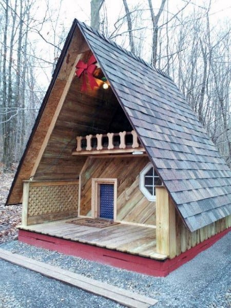Wooden A-frame dog house with shingled roof and porch