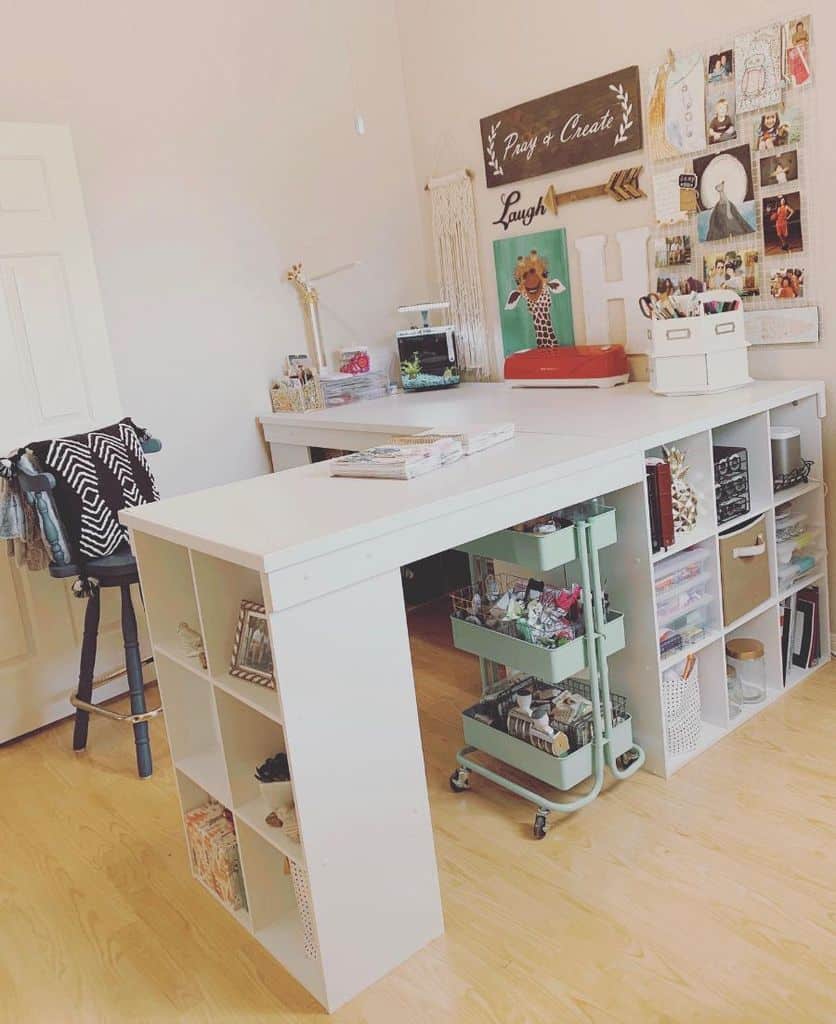 Spacious craft room with a modern white island desk featuring cubby storage, a rolling cart for tools, and personalized decor for creative inspiration