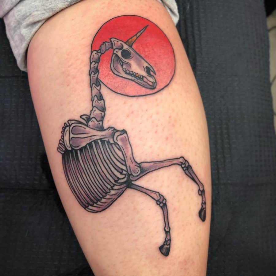 Bold black and red tattoo of a unicorn skeleton rearing up, set against a red circular background, blending fantasy with an eerie aesthetic.