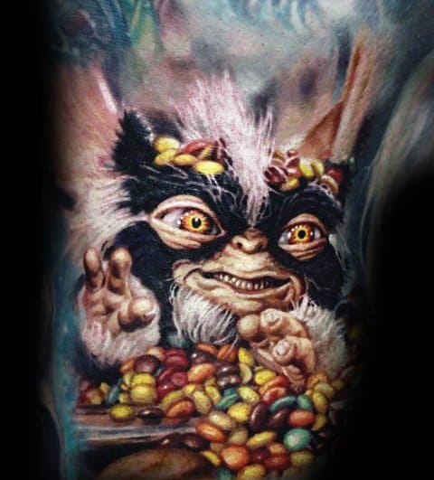 Realistic Gremlin tattoo with black-and-white fur, glowing eyes, and a playful grin, surrounded by colorful candy.