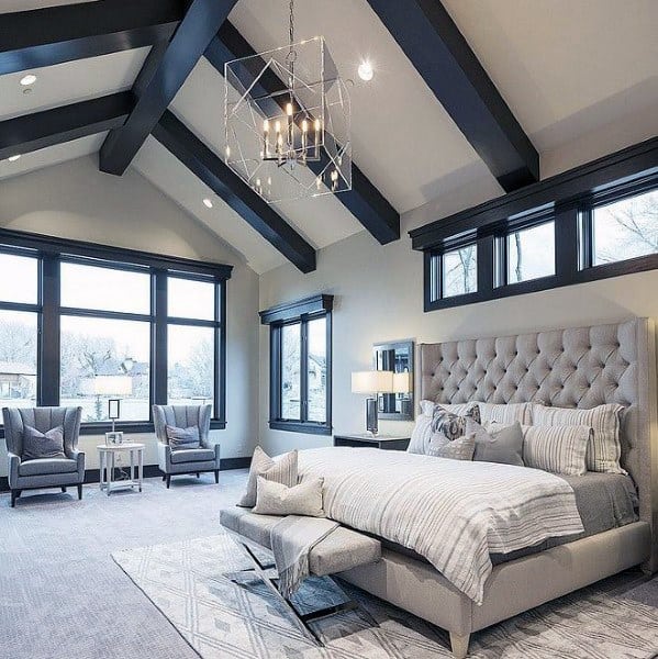 Elegant bedroom with vaulted ceiling, tufted bed, and modern chandelier.