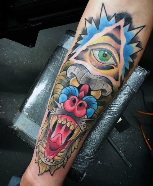 Surreal baboon tattoo with bold colors, fierce expression, and an all-seeing eye, blending neo-traditional and mystical elements on the forearm.