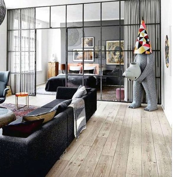 Living room with hardwood floors, glass partition, and quirky bear sculpture.