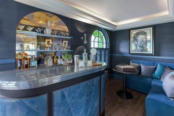 Retro-inspired home bar with mirrored backsplash, curved metallic countertop, and blue decor accents.
