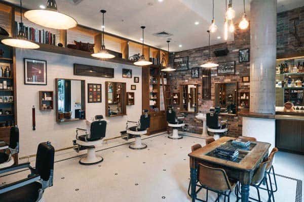 Library-themed barber shop with vintage chairs, bookshelf decor, and brick accent walls.